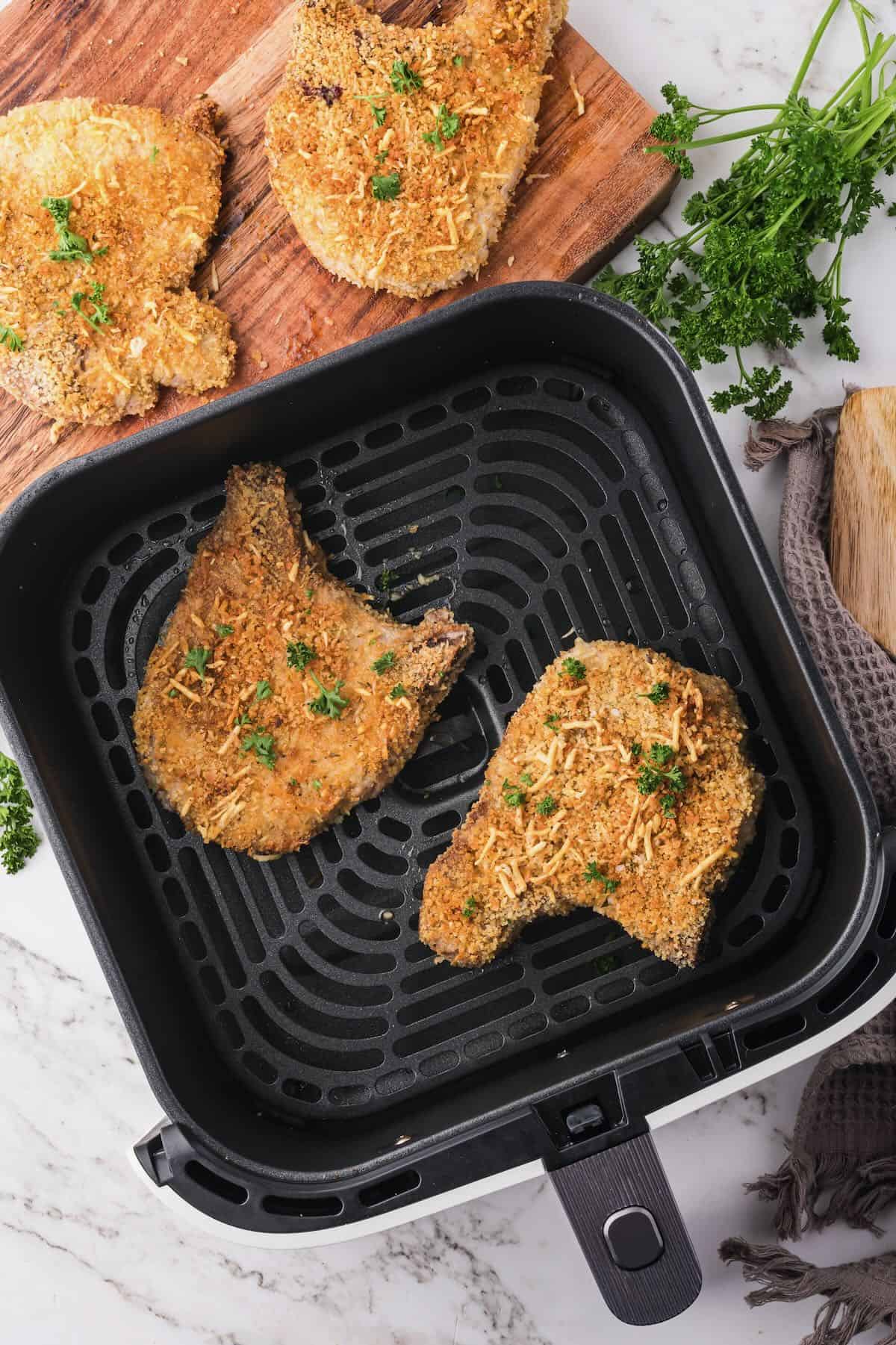 An air fryer basket with crispy pork chops.