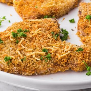 Air fryer pork chops with golden brown crispy breading on a white plate.