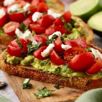 A piece of toast topped with mashed avocado and cherry tomatoes.