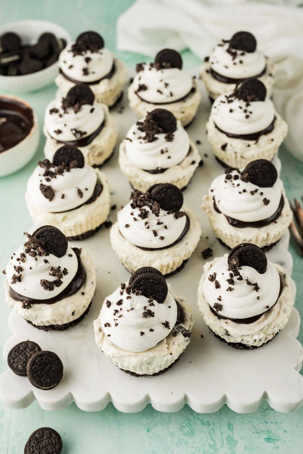 A dozen mini Oreo cheesecakes topped with whipped topping and mini Oreo cookies. 