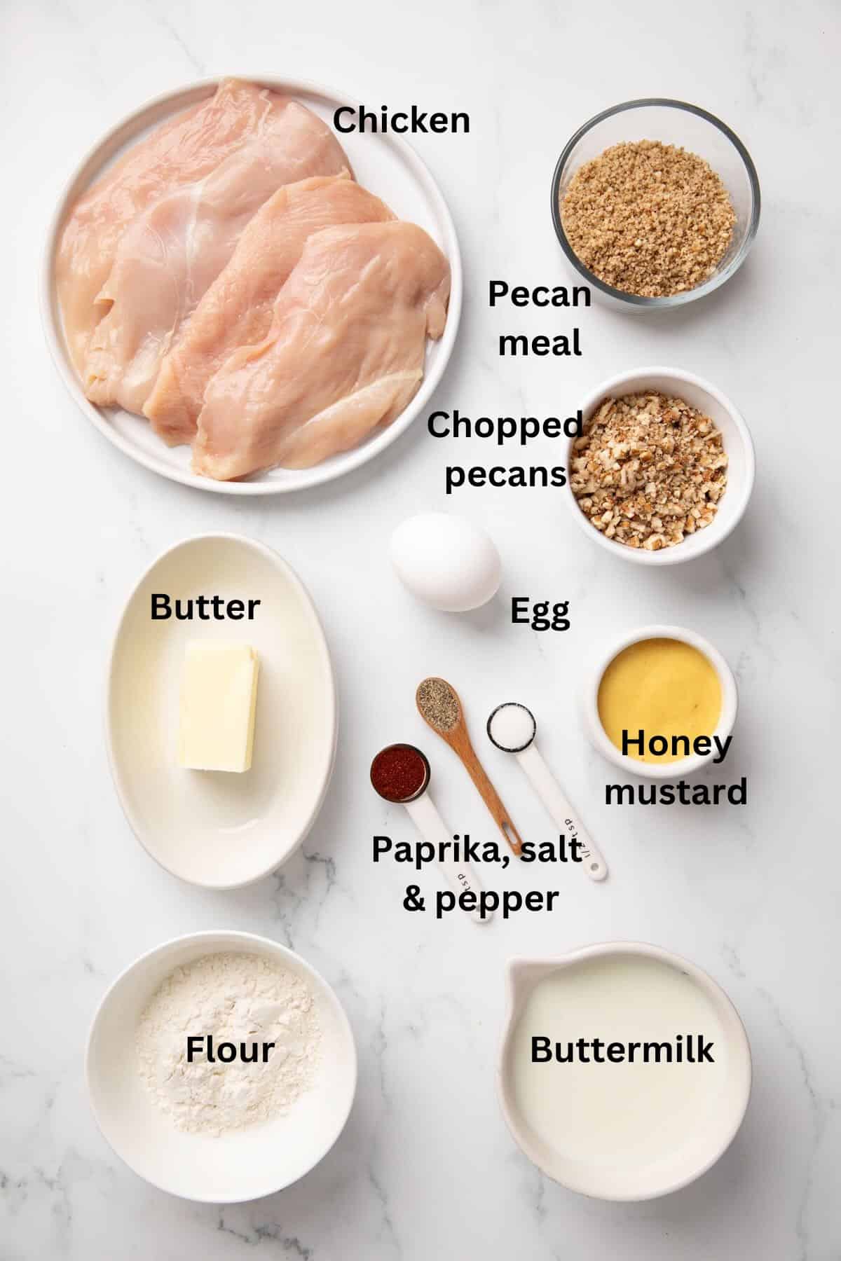Ingredients for pecan crusted chicken including chicken breasts, buttermilk, flour and chopped pecans.