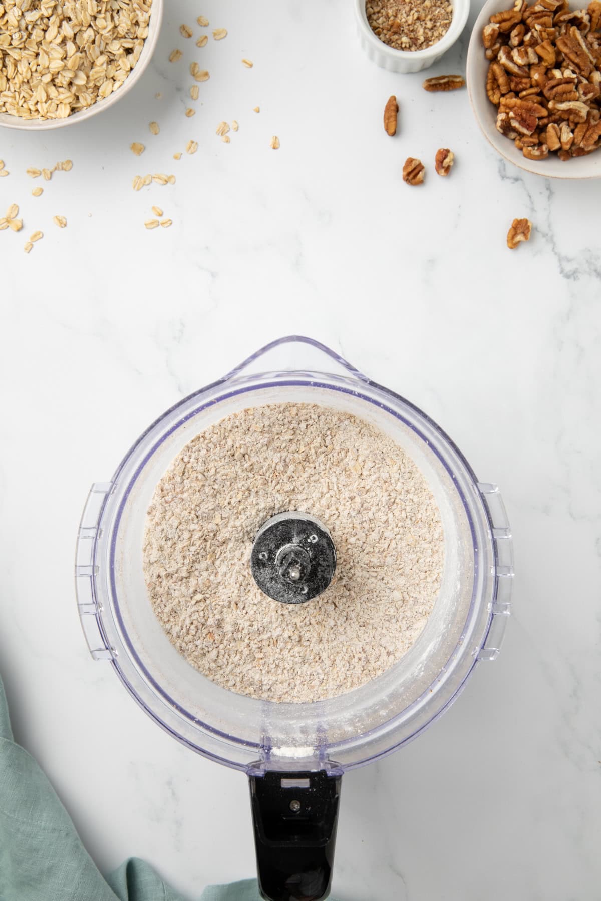 Flour and other dry ingredients are added to oat flour in a food processor. 