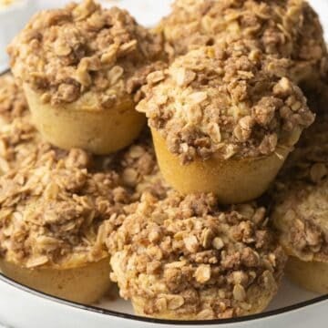A stack of cinnamon oatmeal muffins topped with a pecan and oatmeal crumble.