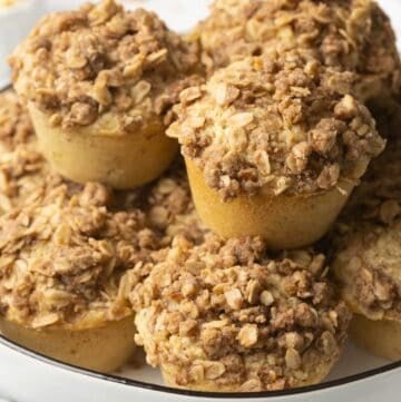 A stack of cinnamon oatmeal muffins topped with a pecan and oatmeal crumble.