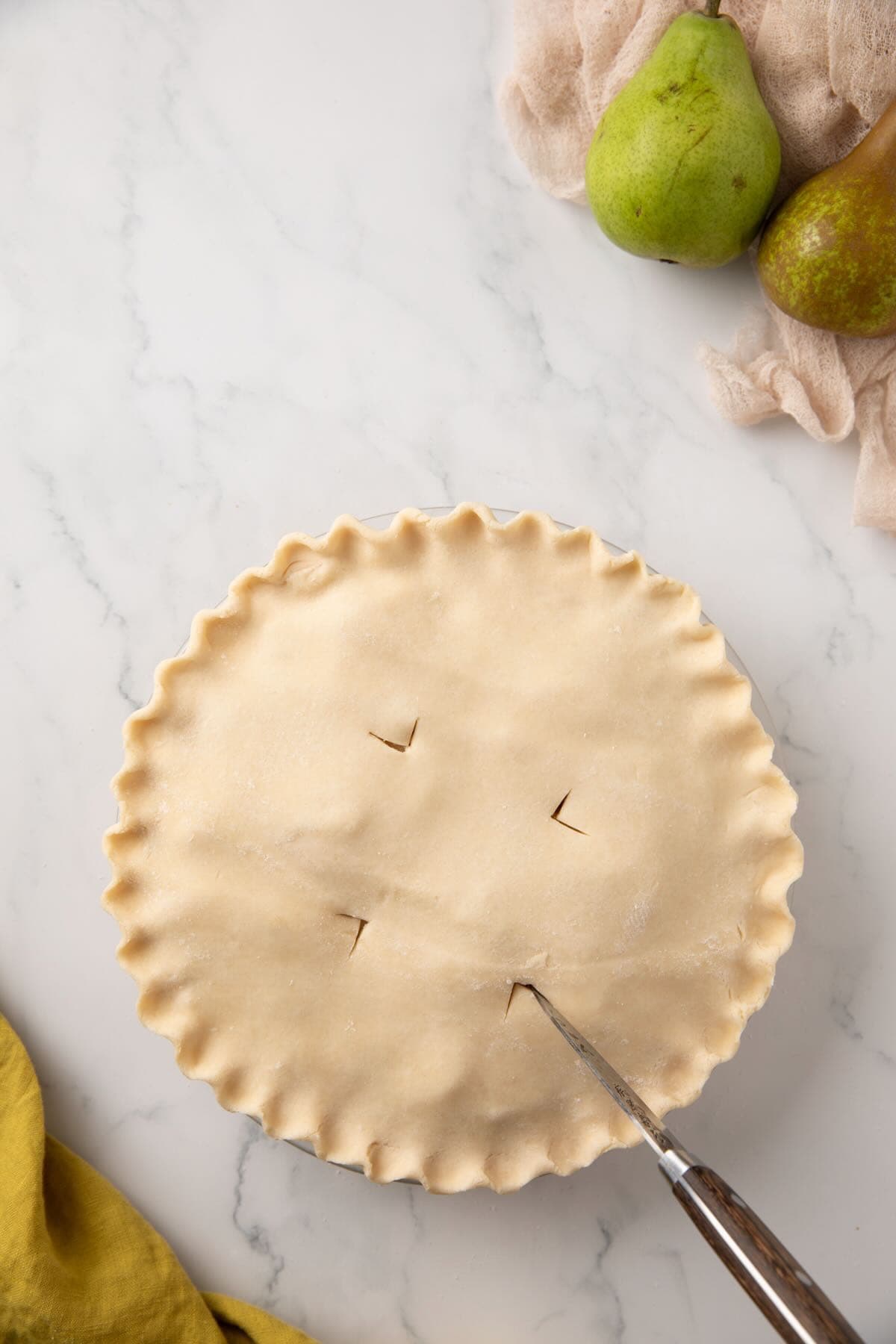 Using a knife to cut slits in the unbaked top crust of a pie. 