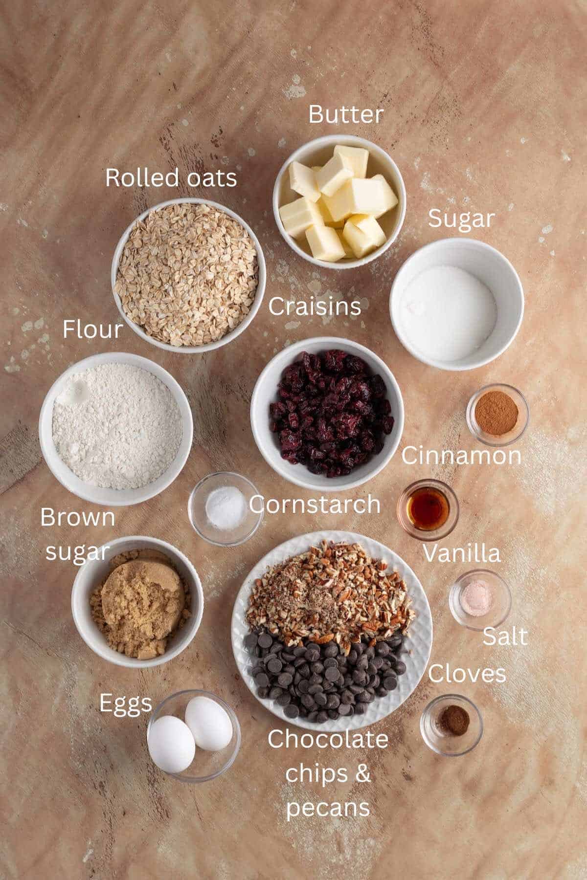 Bowls of ingredients, including chocolate chips, Craisins, oatmeal, sugar, flour, vanilla extract, and brown sugar for cookies.