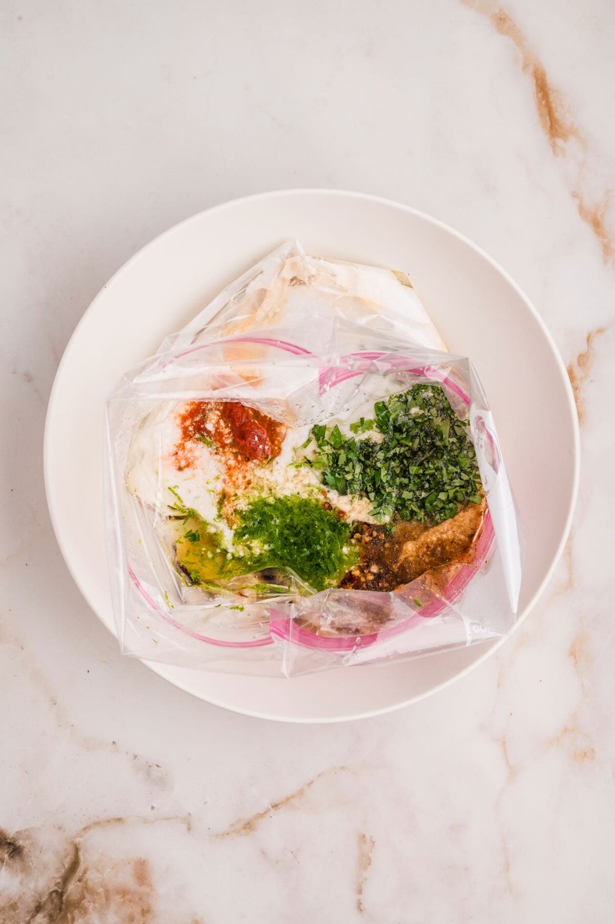Chicken marinade ingredients in a plastic bag include coconut milk, lime juice, cilantro, and spices. 