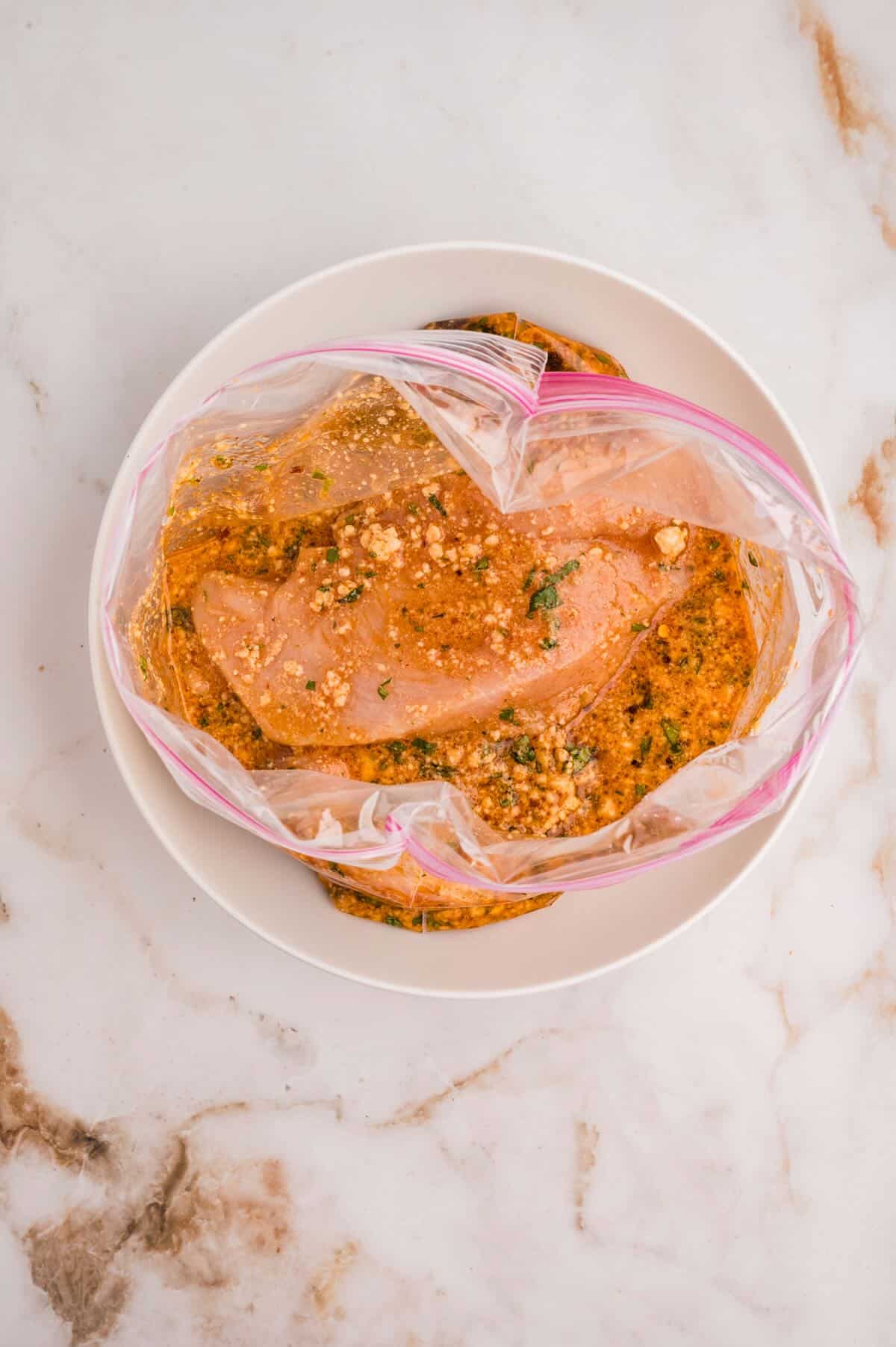 Chicken breast in a plastic bag full of coconut lime marinade. 