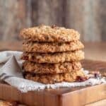 A stack of five Oatmeal Cranberry Chocolate and Pecan Cookies on a cutting board.