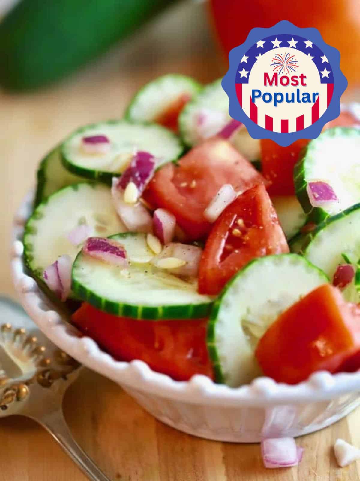 Southern Cucumber and Tomato Salad in a white bowl with a tomato and cucumber in the background