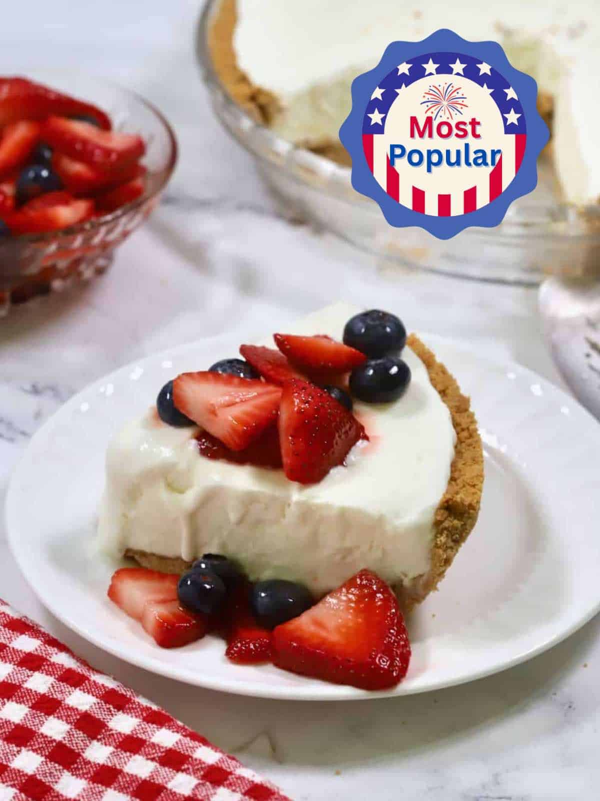 A slice of frozen lemonade pie topped with sliced strawberries and blueberries. 