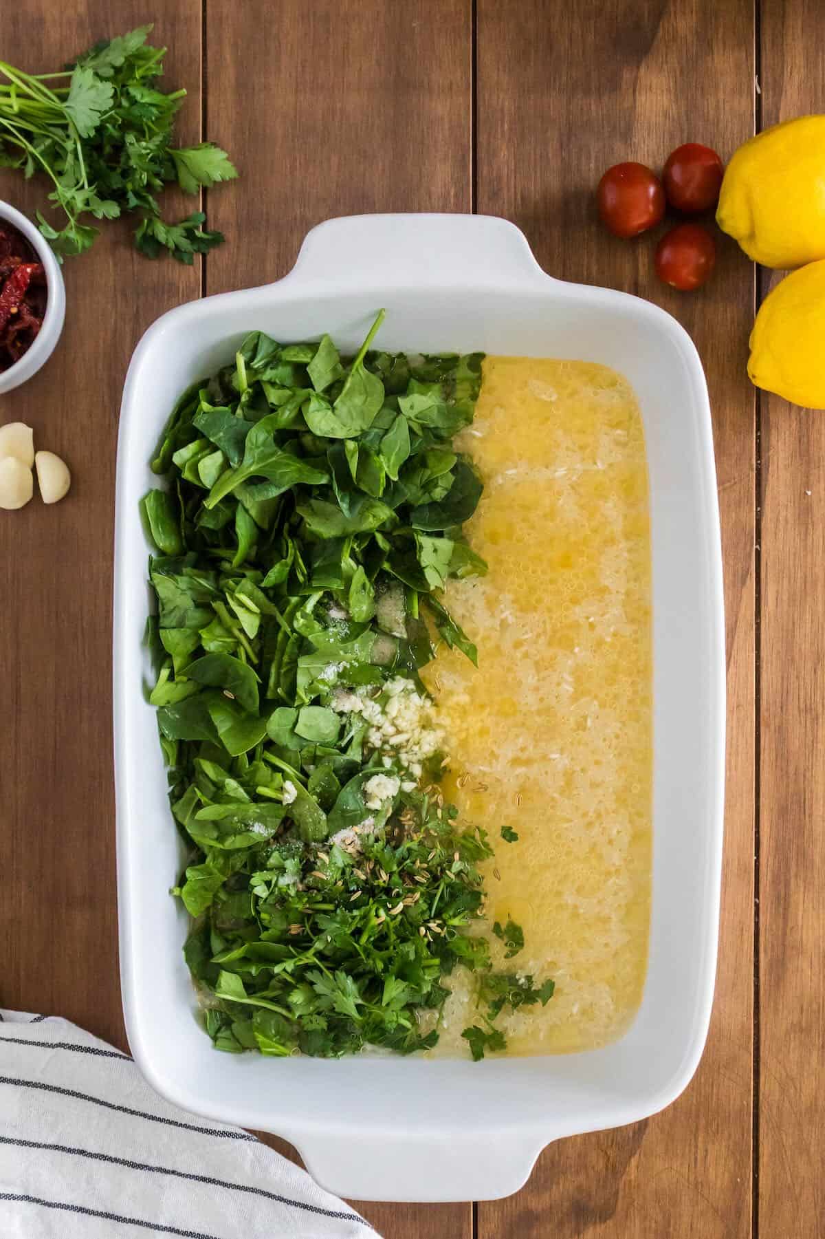 Rice, chicken, stock, and spinach in a baking dish. 