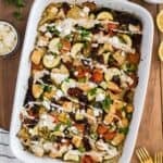 A white baking dish with baked Mediterranean Chicken and Rice Casserole topped with tahini sauce.