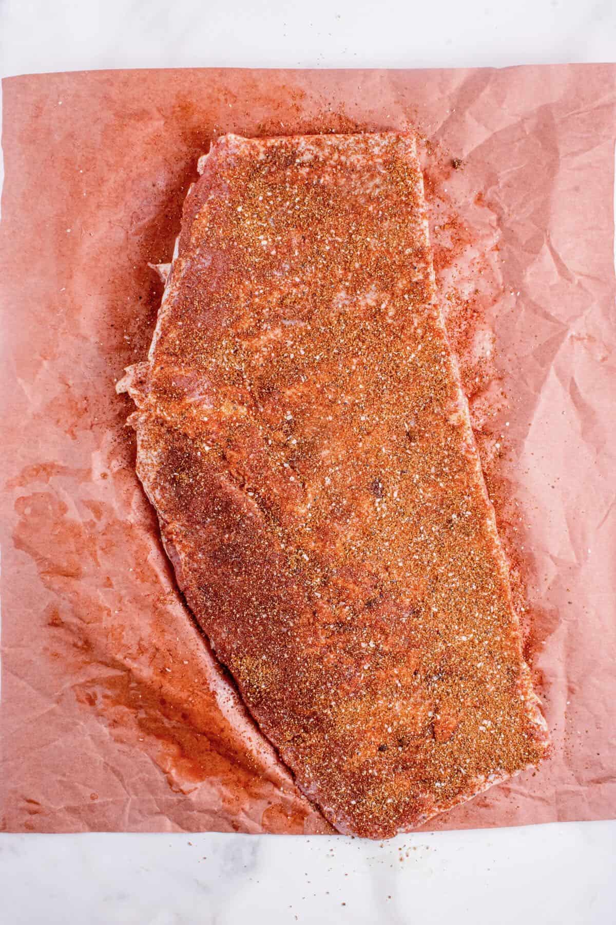 A rack of spare ribs topped with a dry rub. 