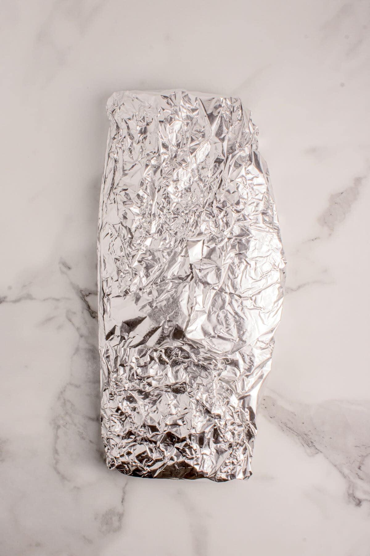 A rack of ribs wrapped up with aluminum foil.