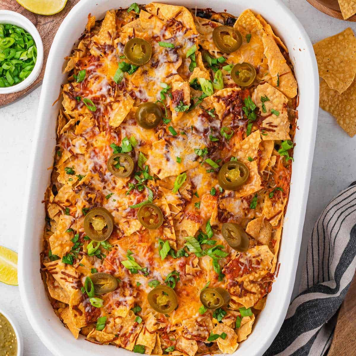 A white ceramic baking dish filled with baked chicken taco casserole, garnished with cilantro.