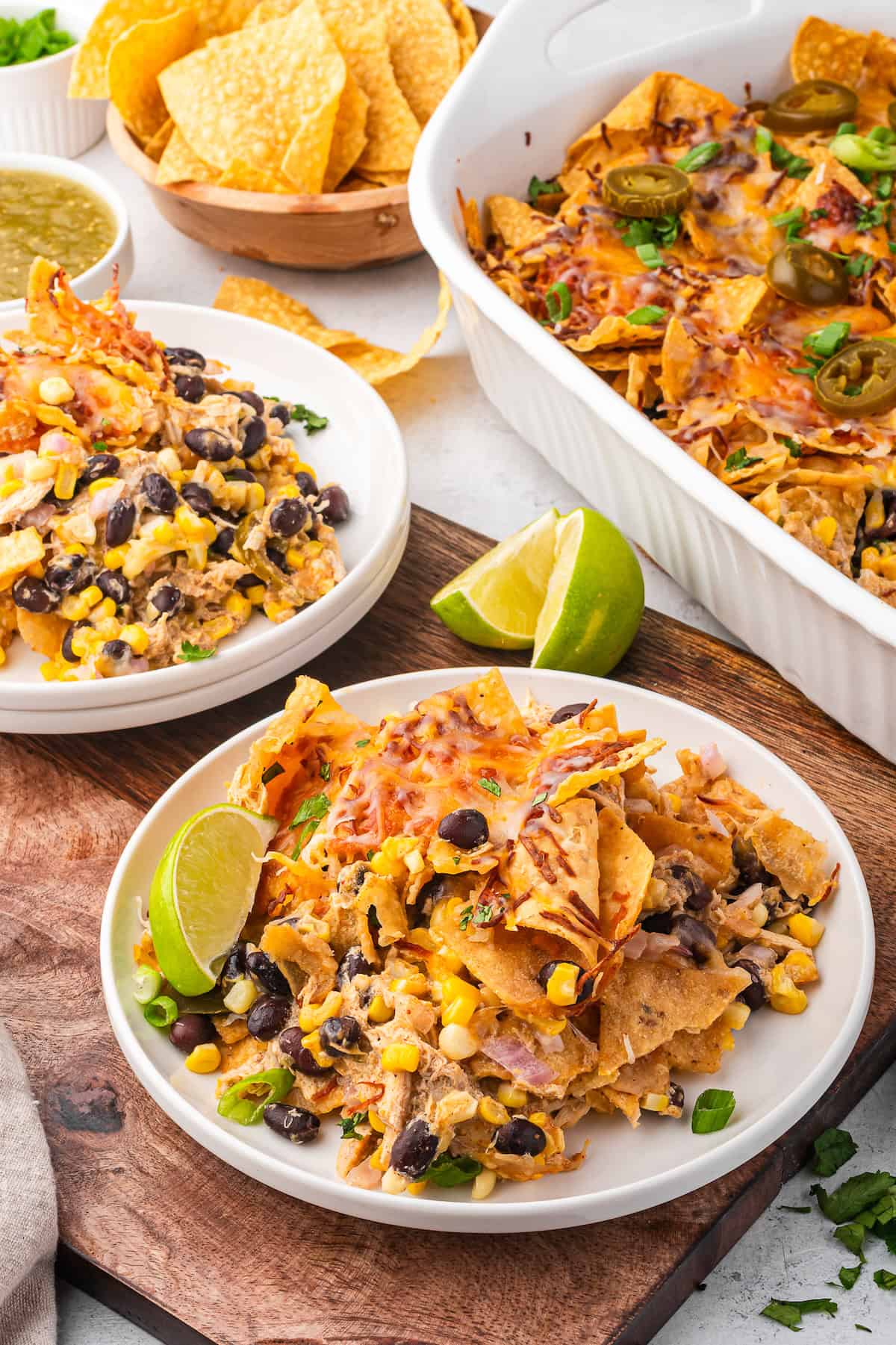 Two servings of chicken taco casserole on white plates next to a casserole dish.