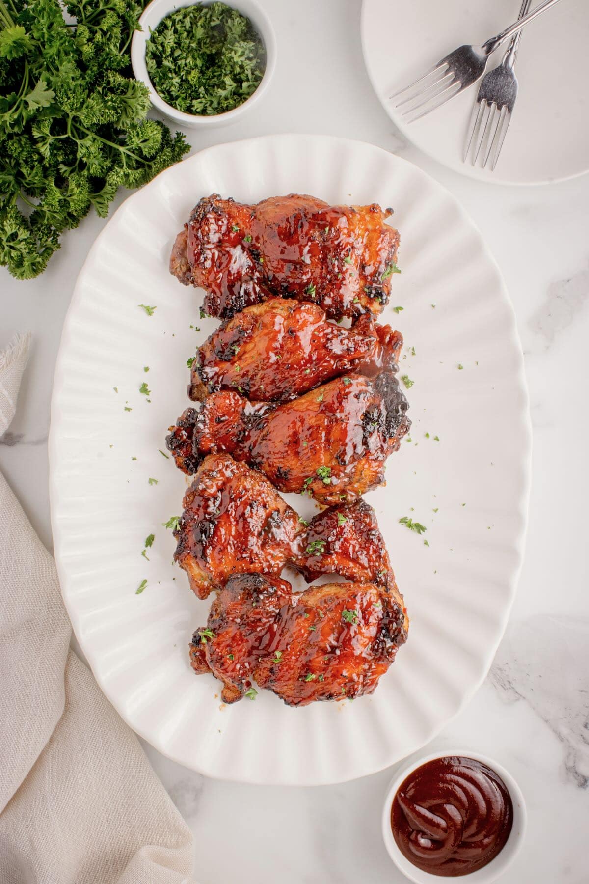 Grilled BBQ'd chicken thighs resting on a plate before being served