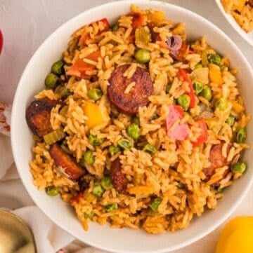 A large serving of cooked Cajun chicken and rice with bell peppers, onions, and other vegetables surrounding it.