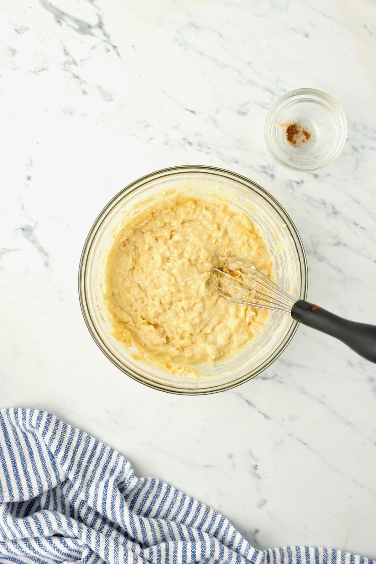 Mini cornbread muffin batter in a glass bowl with a whisk. 