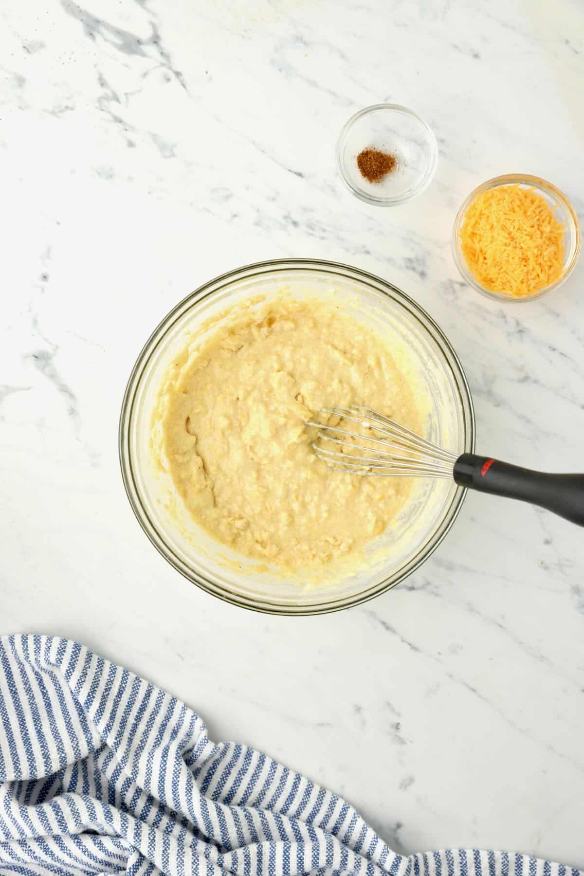 Jiffy mix added to sour cream, creamed corn, and an egg in a glass bowl. 