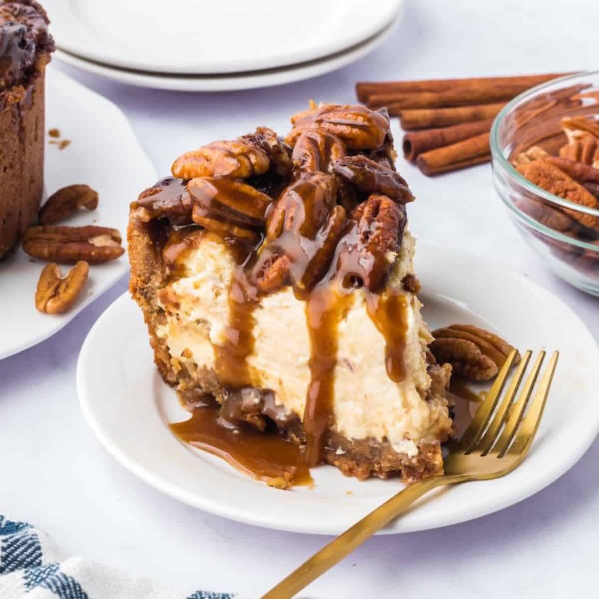 A slice of pecan pie cheesecake topped with pecans and a gooey topping on a plate with a fork.