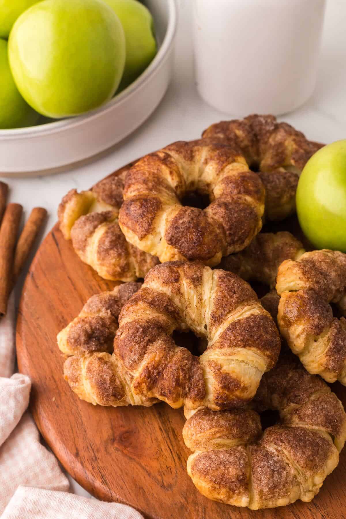 A wooden cutting board with baked apple pastries cooling.