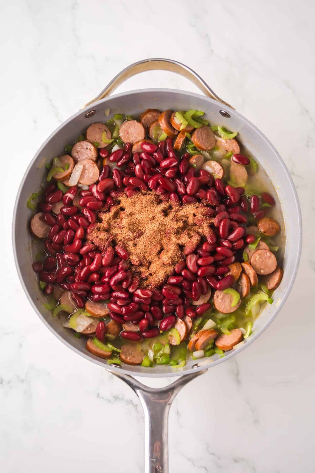 A skillet full of the holy trinity, sliced sausage, and red kidney beans. 