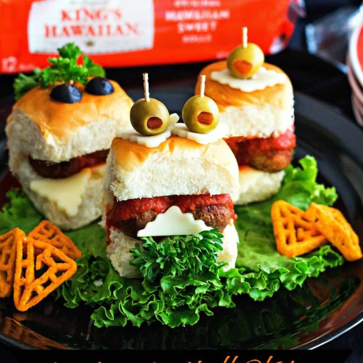 Three meatball sliders on Hawaiian Rolls topped with olive eyes. 