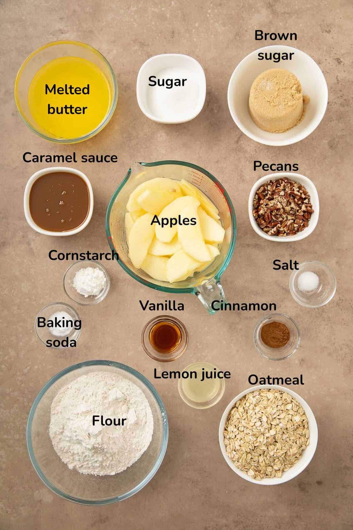 Ingredients for oatmeal apple bars include: sliced apples, oatmeal, flour, sugar, pecans, and caramel sauce. 