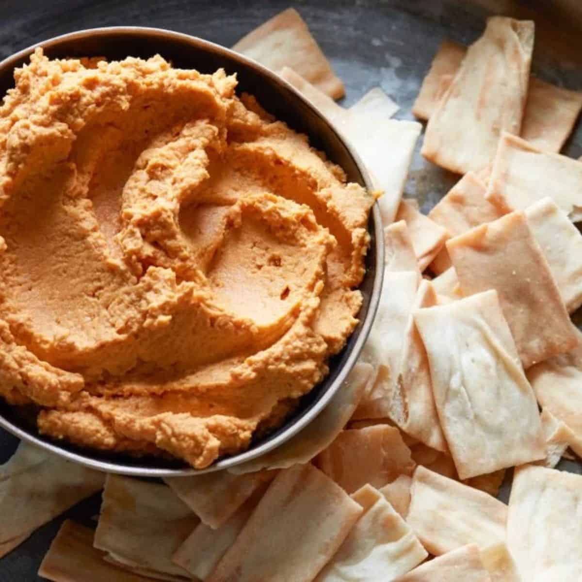 Pumpkin hummus in a bowl with chips. 