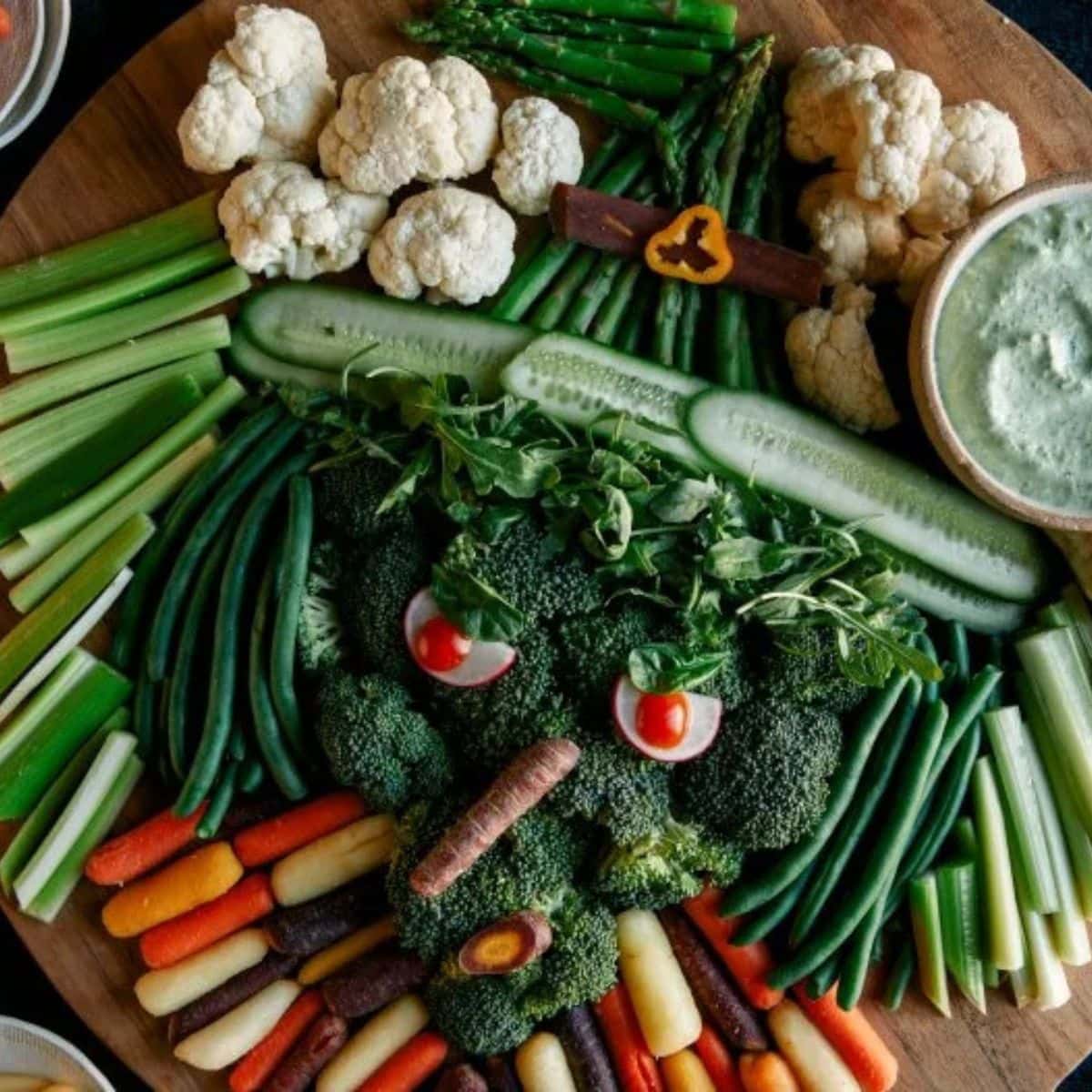 A veggie tray with different veggies that is put together to look like a witch's face. 