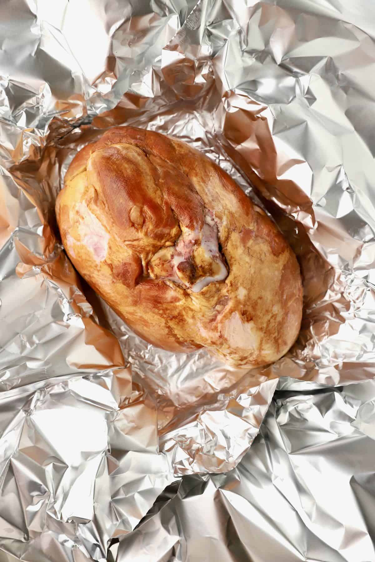 A semi-boneless ham is cut side down in a foil-lined pan. 
