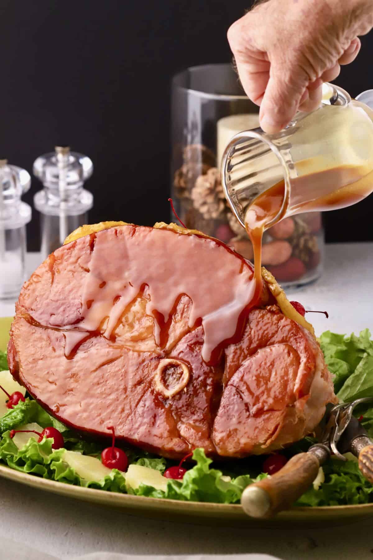Baked Maple Glazed Ham, with the maple glaze being poured over it. 