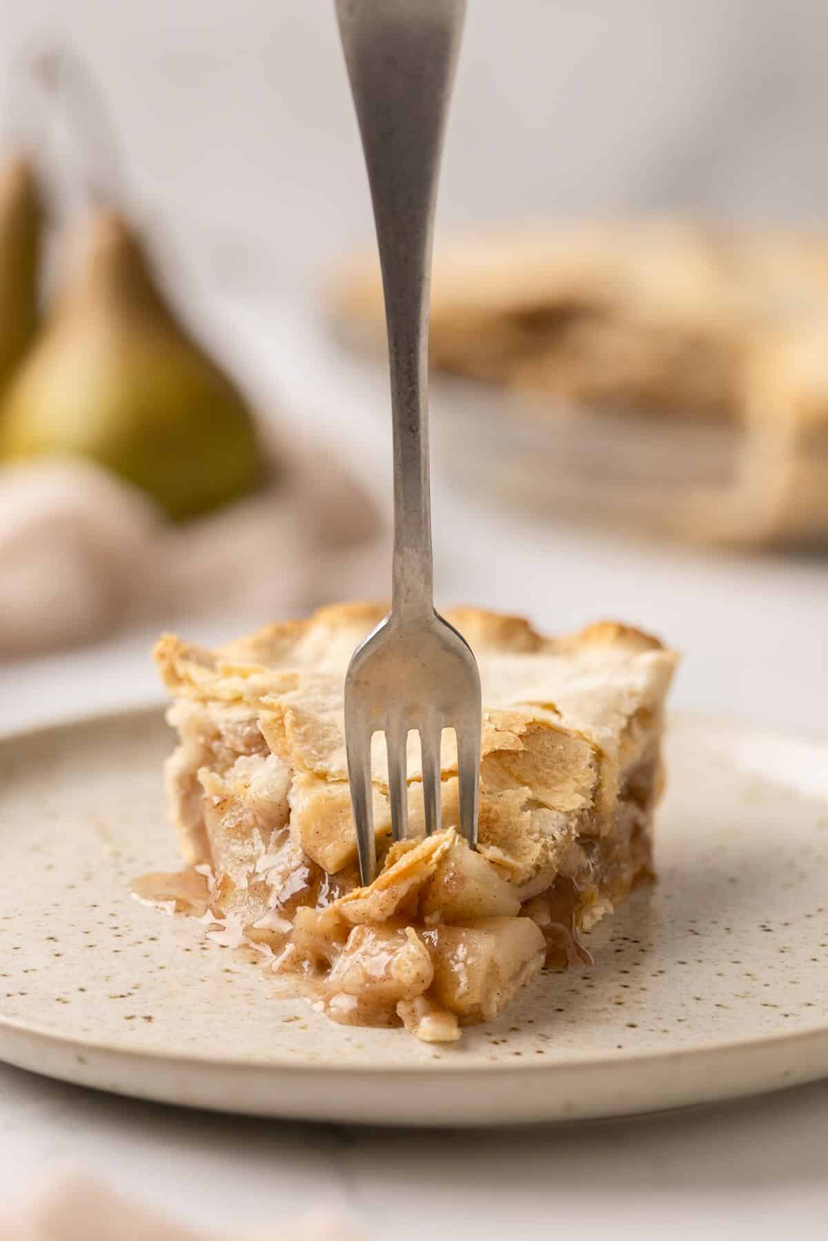 A slice of pear pie on a plate with a fork. 