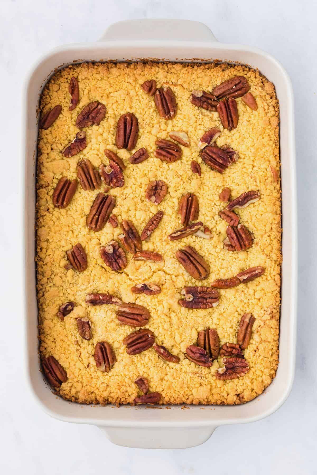 Pecan pie dump cake baked in a white baking dish. 
