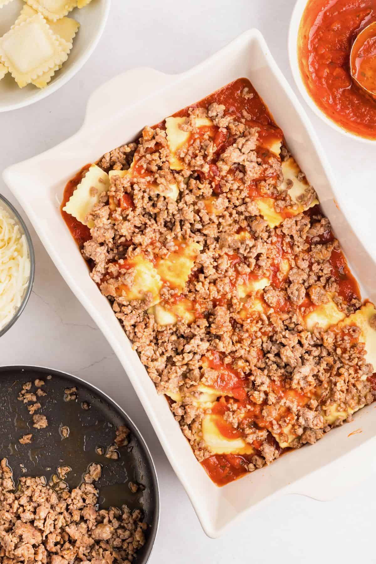 Layer half of the marinara sauce, sausage, and ravioli in a baking dish.