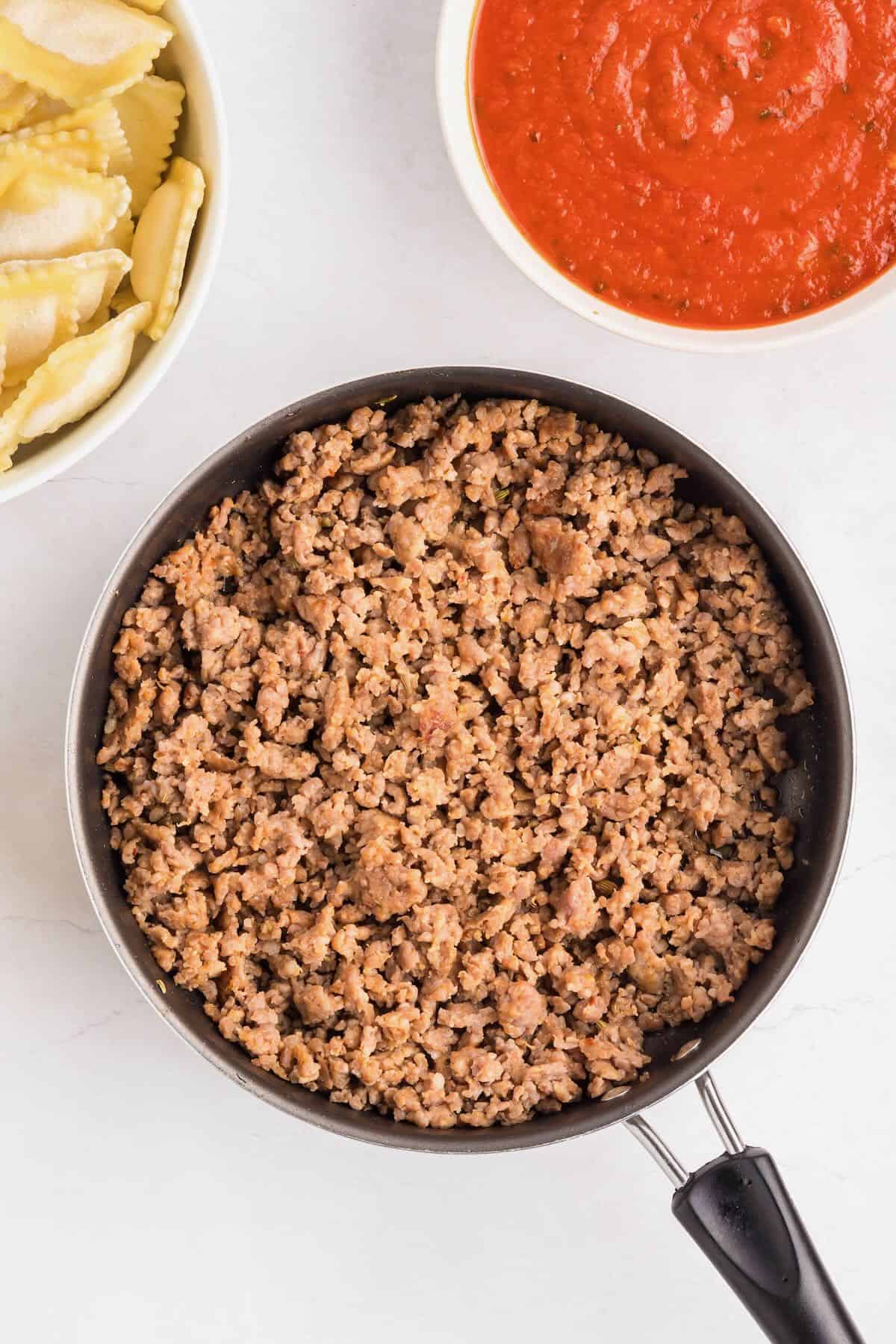 Italian sausage cooking in a skillet.
