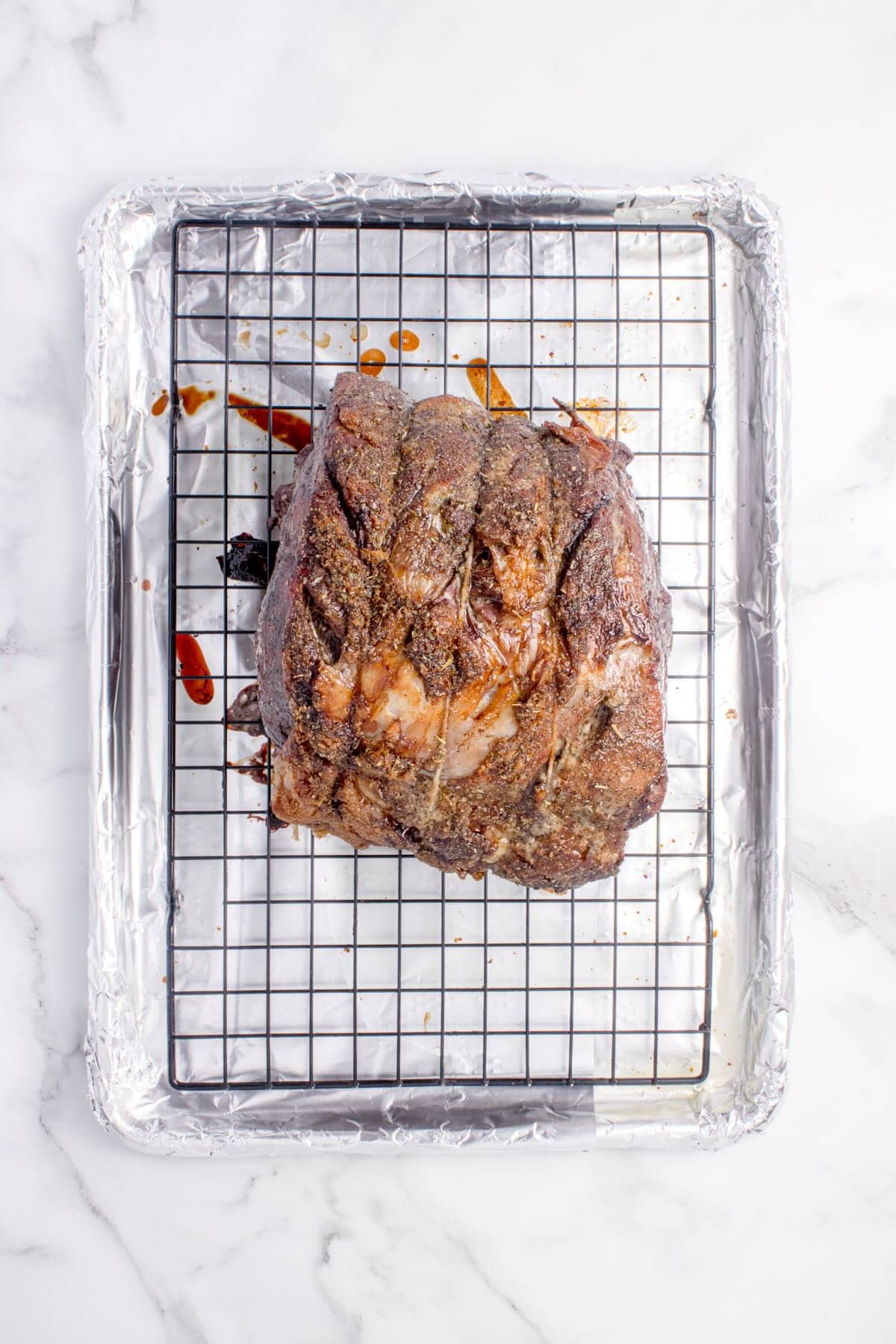 A cooked boneless prime rib roast tied with twine and seasoned on a rack in a baking pan.  