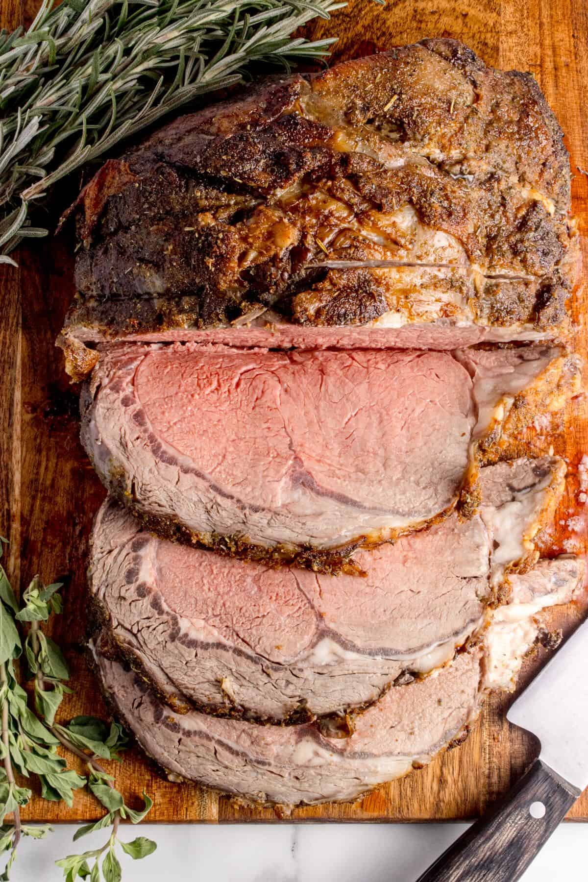 A roasted boneless prime rib roast cut into slices on a cutting board.