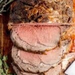 Pinterest pin showing a boneless prime rib roast cut into slices on a cutting board, plus text.