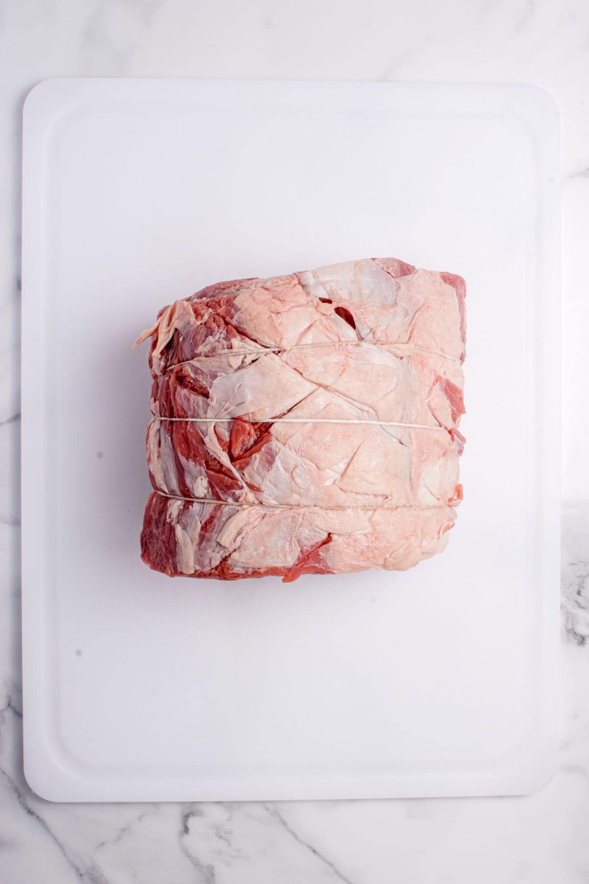 A raw boneless prime rib roast tied with twine. 