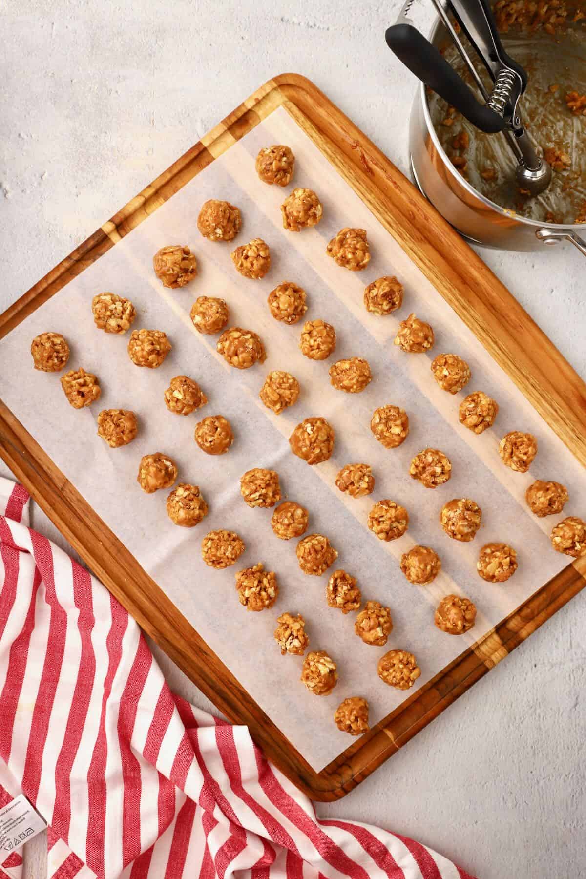 Small balls of melted caramel, Rice Krispies, and pecans on a sheet of parchment paper. 
