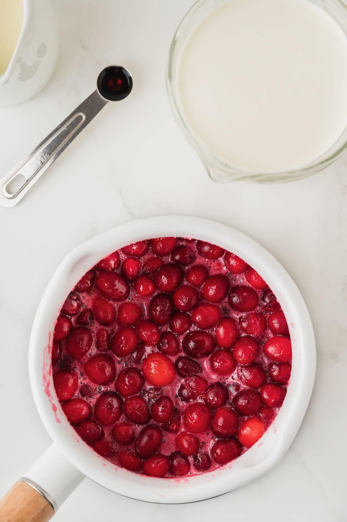 Cooking cranberries sugar and lemon juice in a saucepan on the stove.