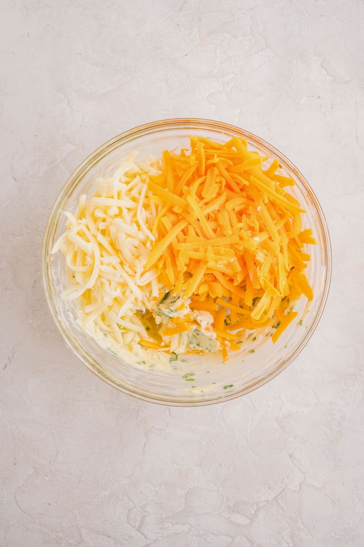 A bowl full of butter, garlic, cheeses, and parsley.