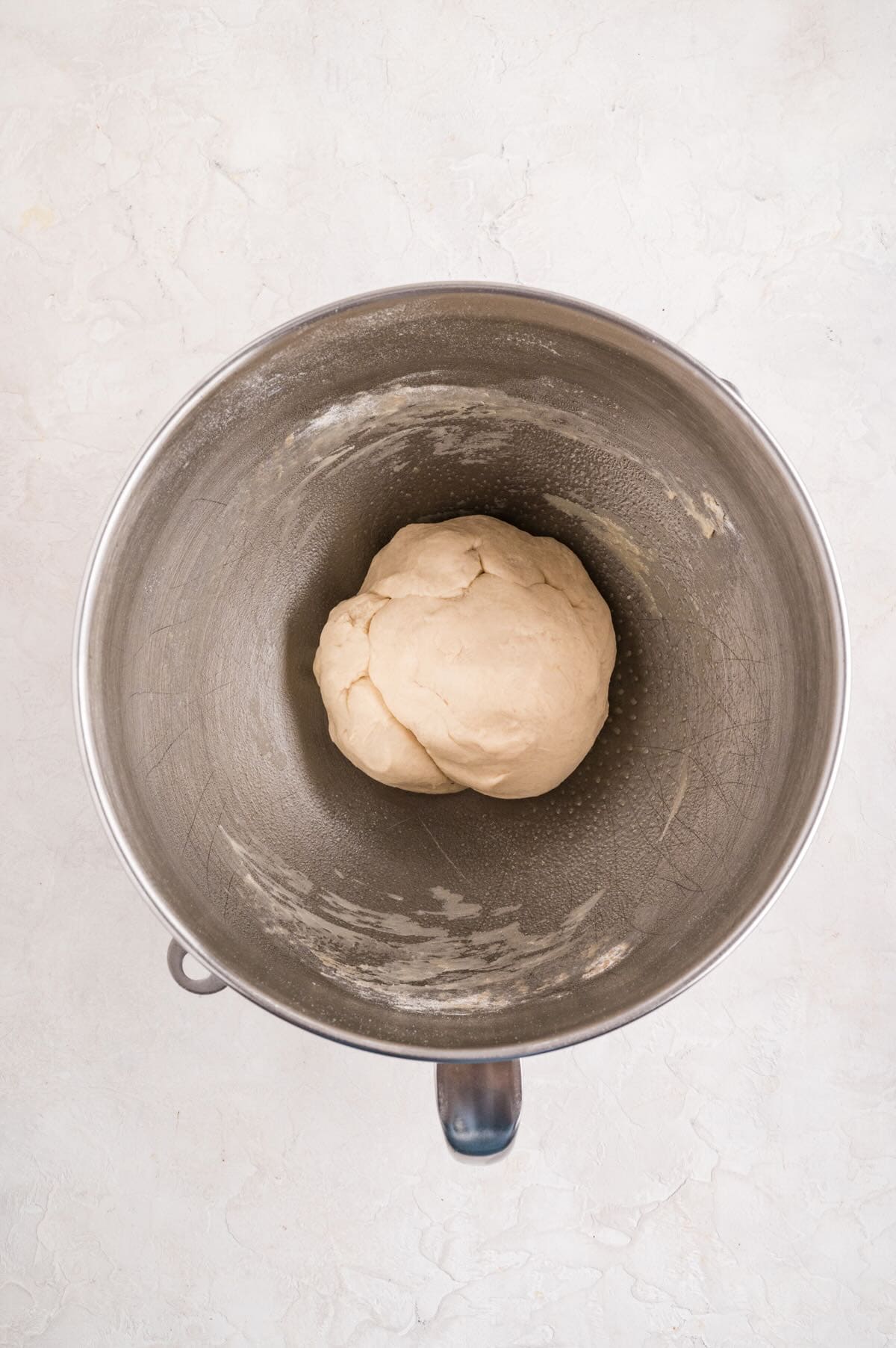 A ball of bread dough in a metal mixing bowl.