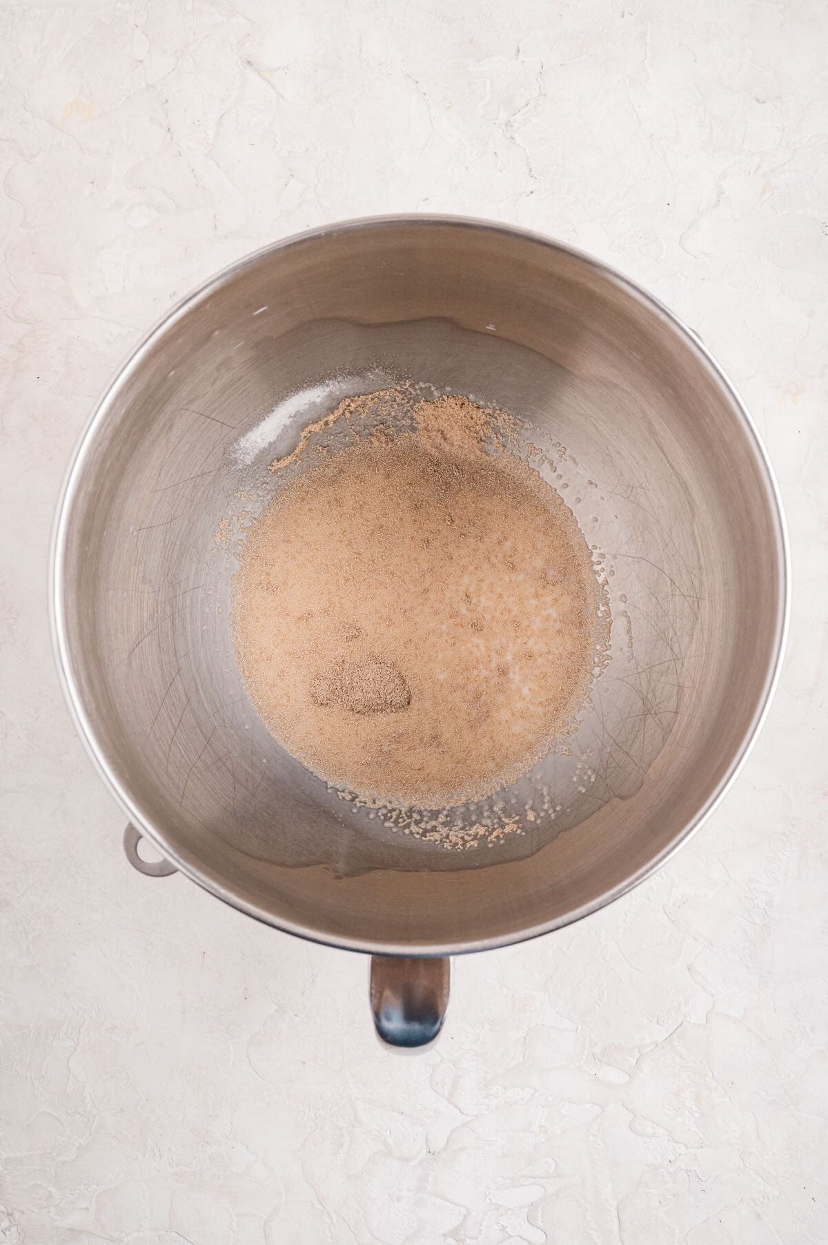 A bowl with water, sugar, and yeast.