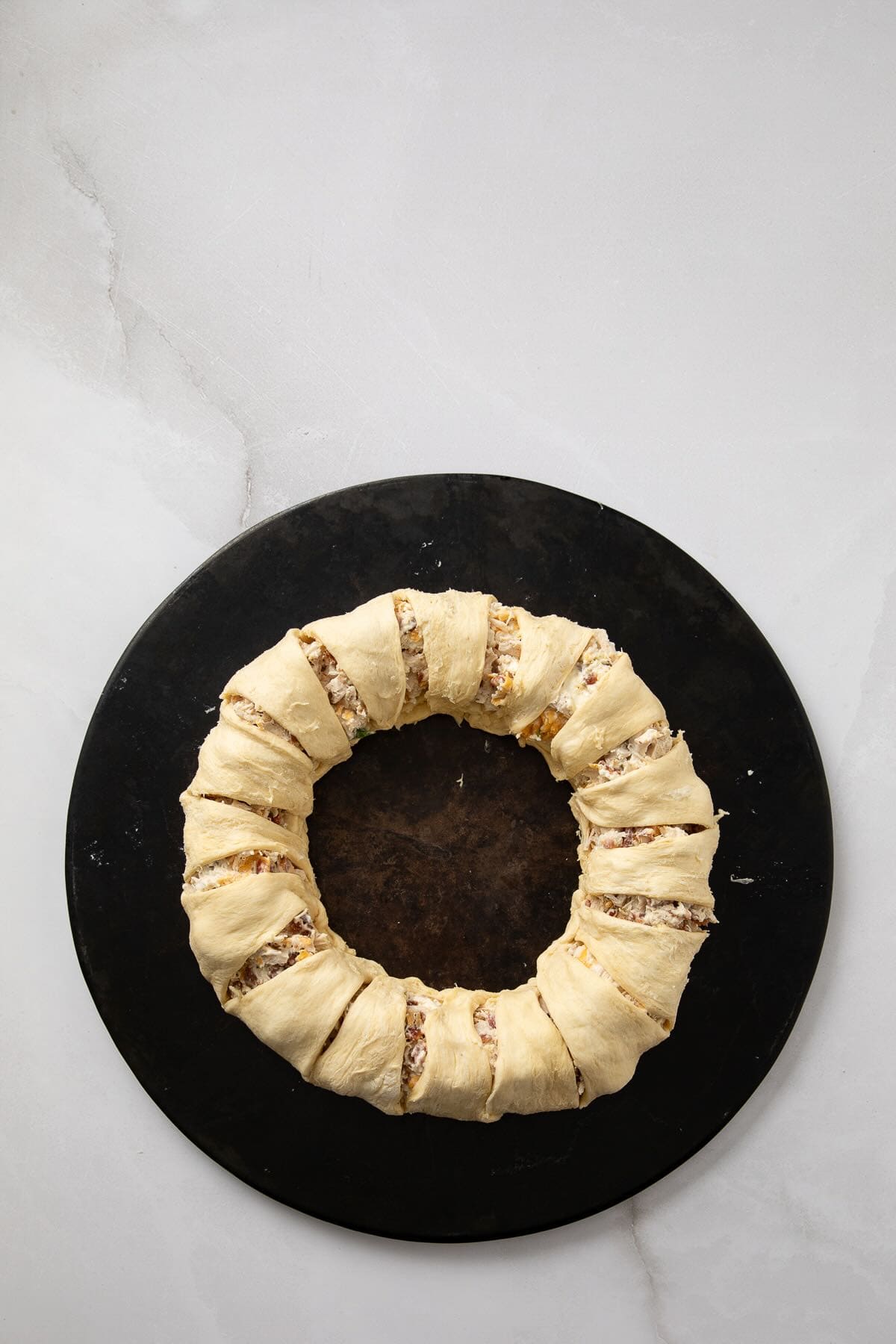 A ring of crescent roll dough wrapped around a filling of chicken, bacon, ranch dressing, and cheeses.