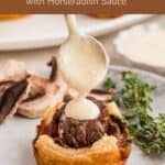 A plate with a mini Beef Wellington Bite topped with horseradish sauce and fresh thyme