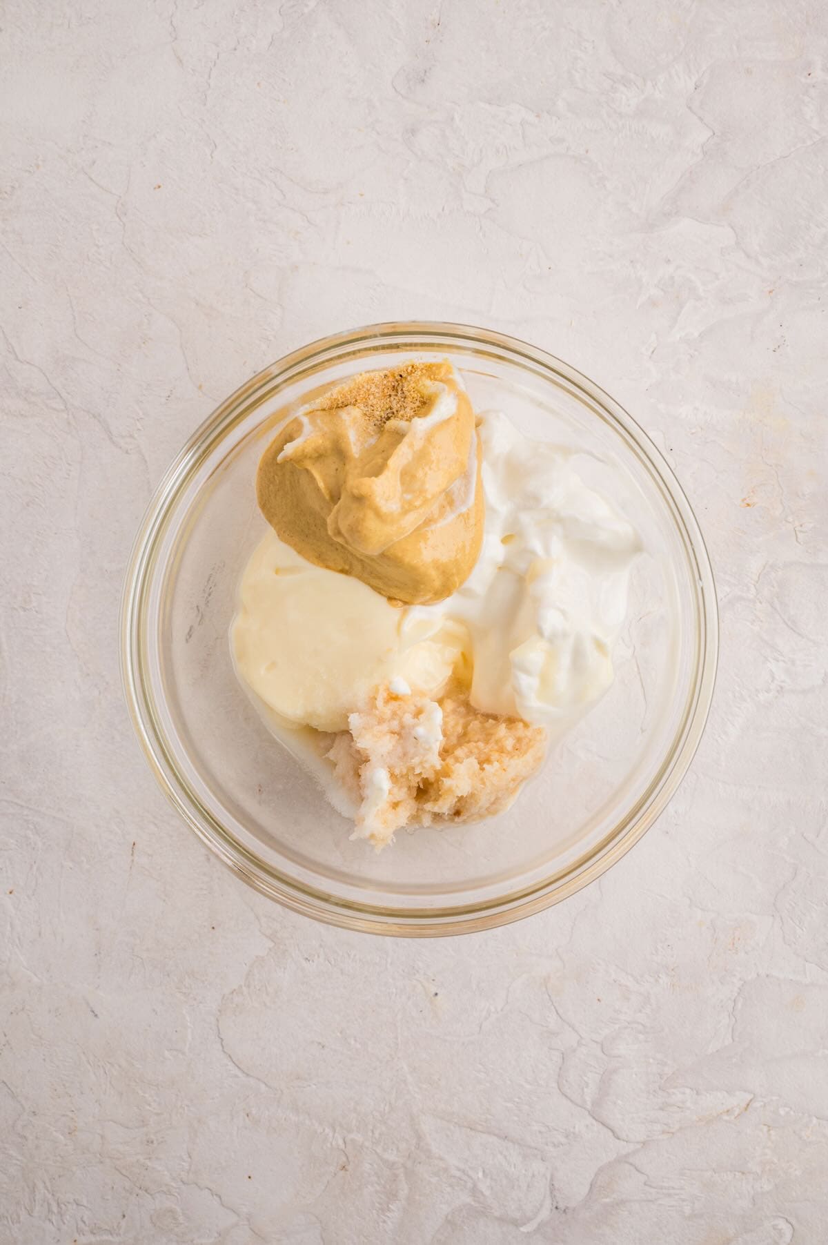 Sauce ingredients in a bowl includes mustard, sour cream, mayo, horseradish and seasoning.